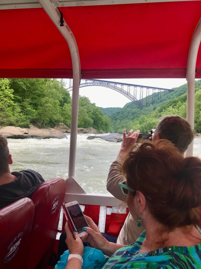 A couple inside the New River Jet Boat admiring the view of the New River Gorge Bridge.