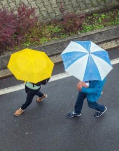 Couple with umbrellas walking through Fayetteville, WV. 