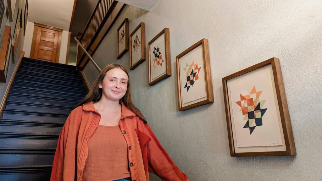 Lindsay Toney standing in the stairwell of Lafayette Flats beside her series of screen prints, "Welcoming Star."