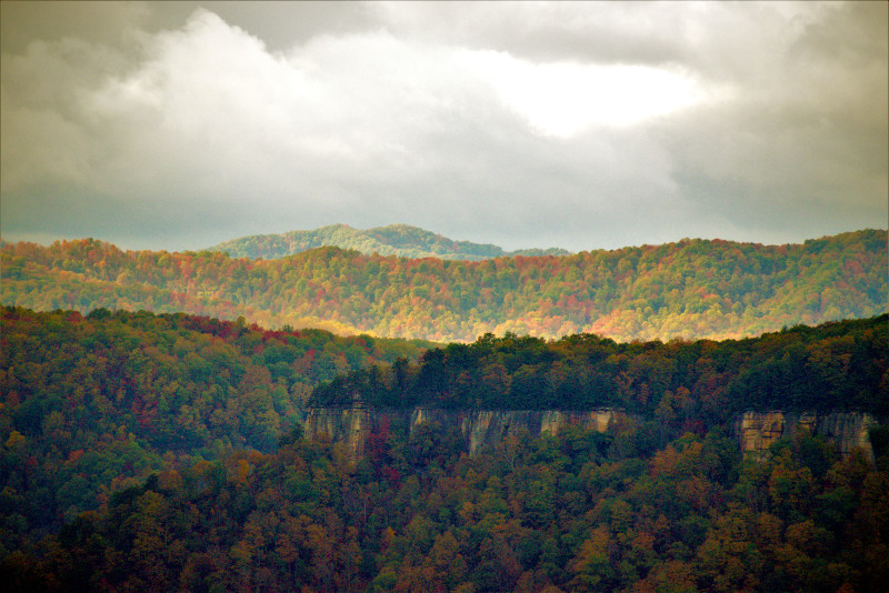 An expansive view of the colorful fall Appalachian Plateau with the sandstone cliffs of the New River Gorge in the foreground.