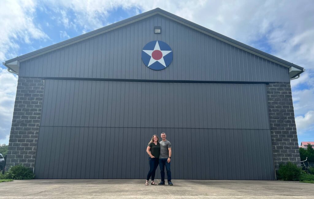 Ashley and Bill Chouinard standing in front of Wild Blue Adventure Co. airplane hanger. 