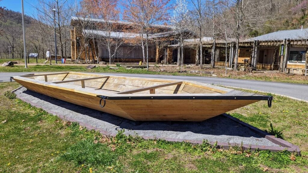 A large, wooden, flat boat known as a batteau sitting in front of the Sandstone Visitors Center. 