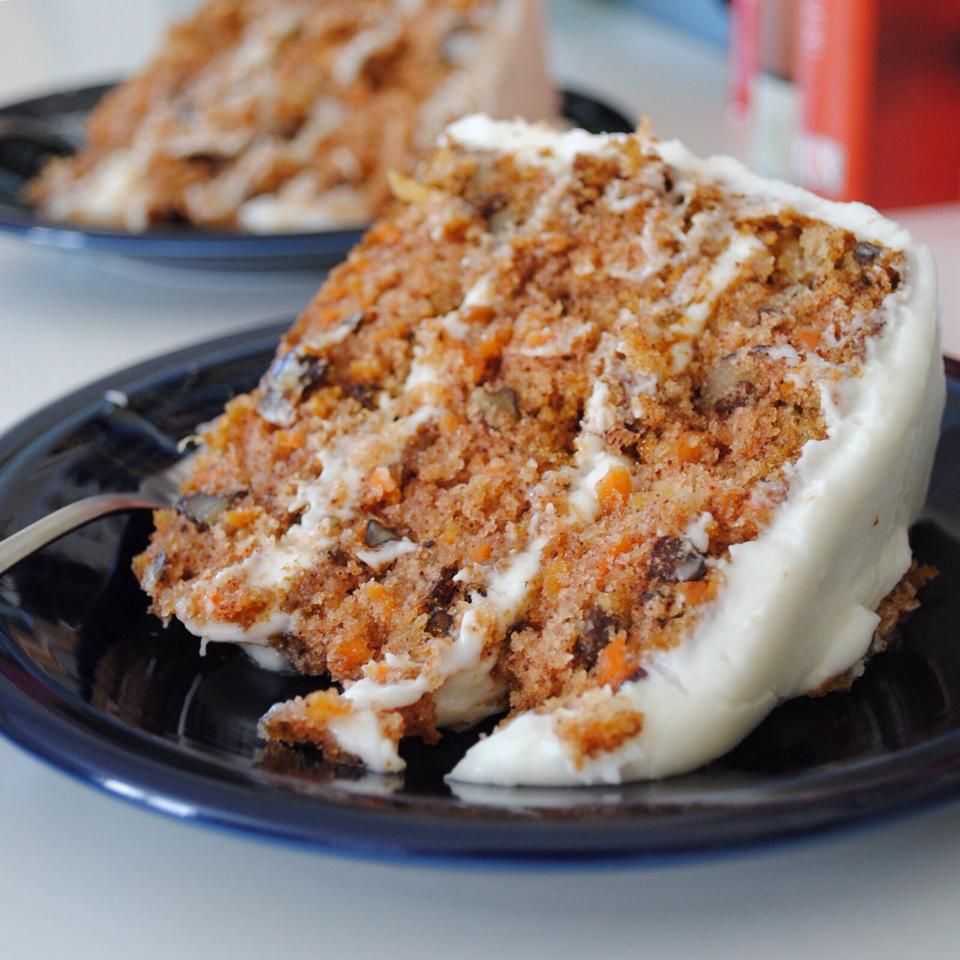 A slice of Cathedral Cafe's carrot cake, It's full of nuts, carrots and spices with white cream cheese icing on top. 