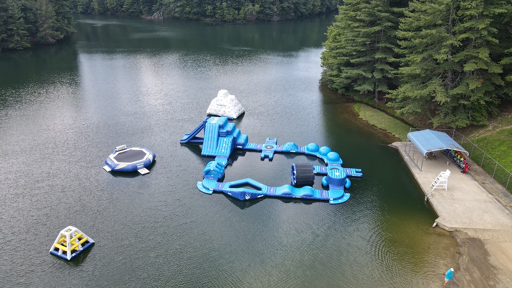 A big lake surrounded by pine trees with blue inflatable water toys and tubes near Beckley, WV. 