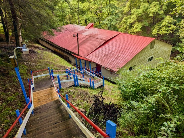 A very large red-roofed building sits in a forest alcove in Ansted, WV. There is a long set of stairs leading to the roller skating rink. 