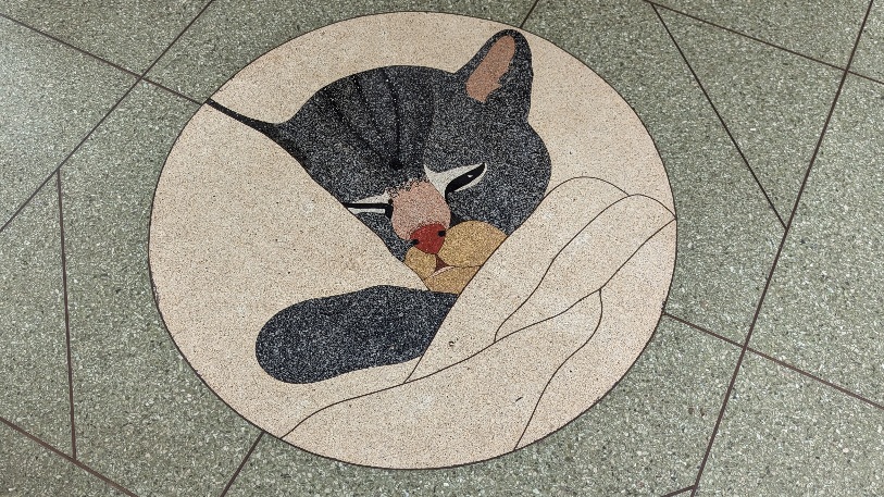 Shades of grey and beige floor tiles create a mural of a Chessie cate on the floor of the Prince, WV train depot. 